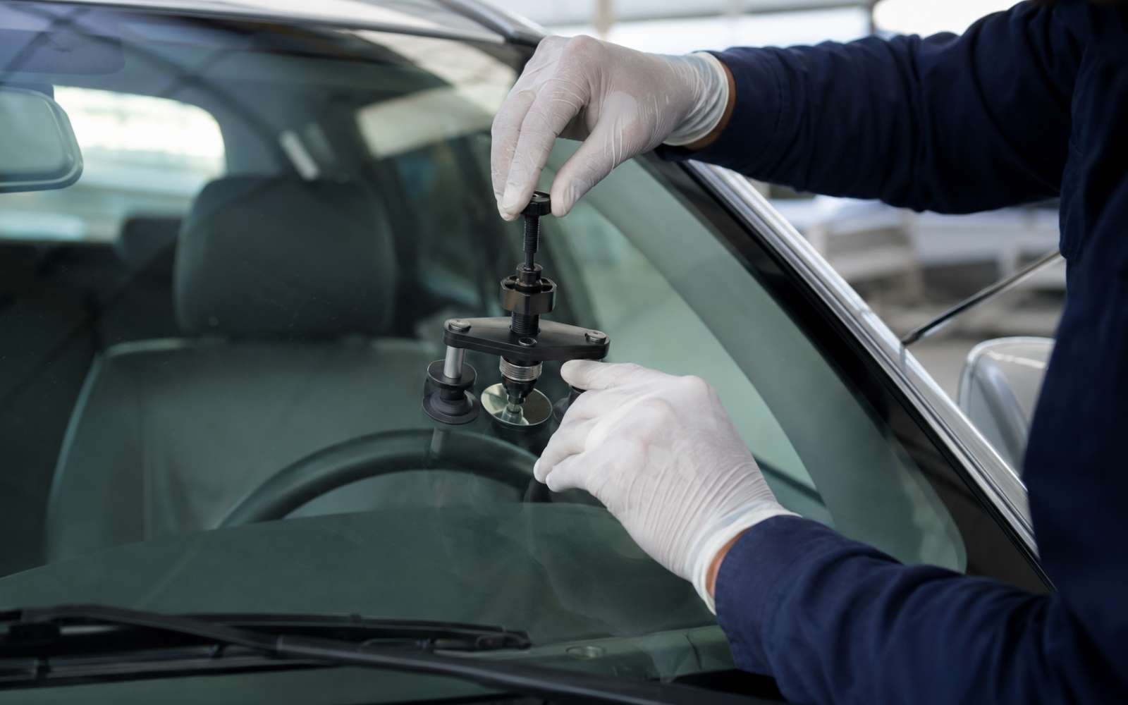 Auto glass technician setting a windshield with a suction tool in San Mateo, CA